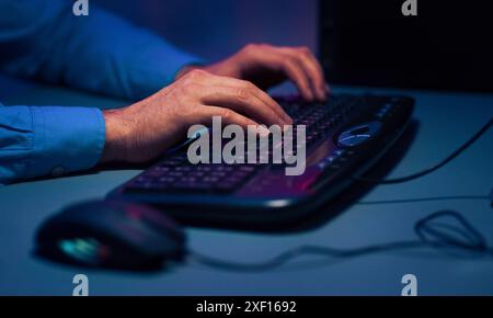 Mans Hands Typing on a Keyboard in a Dark Room Stock Photo