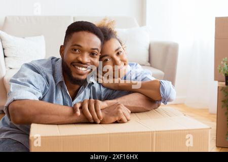 Afro Spouses Embracing Among Unpacked Moving Boxes In New Flat Stock Photo