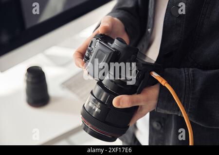 Close up shot of male hands holding professional camera and looking at photographs at camera screen, copy space  Stock Photo