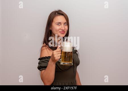 Beautiful woman holding a beer mug on light background Stock Photo