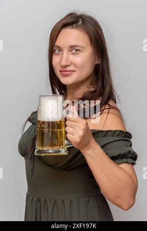 Beautiful woman with a beer mug in her hand on light background. Concept: beer festival and holiday. Stock Photo