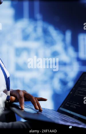 System administrator writes code on laptop to visualize artificial intelligence neural networks using augmented reality, close up. High tech facility worker runs AI script for information processing Stock Photo