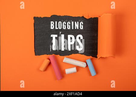 Blogging Tips. Text under torn orange paper on a blackboard. Stock Photo