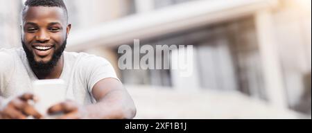 Man Smiling At Phone On Urban Street Stock Photo