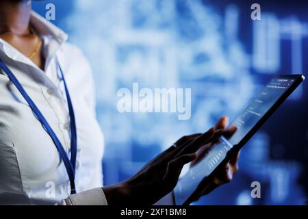 BIPOC computer operator writes code on tablet to visualize artificial intelligence neural networks using augmented reality. High tech workplace executive runs AI script for information processing Stock Photo