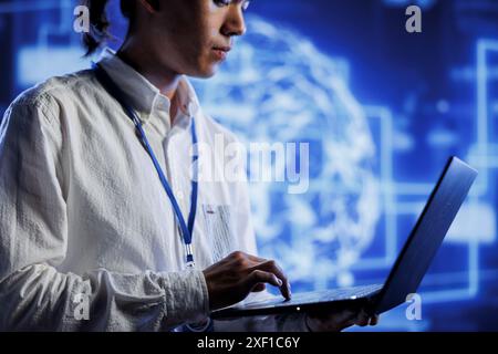 System administrator using laptop to maintenance artificial intelligence neural networks simulating human thought processes in computerized model. Adept professional doing checkup on AI systems Stock Photo