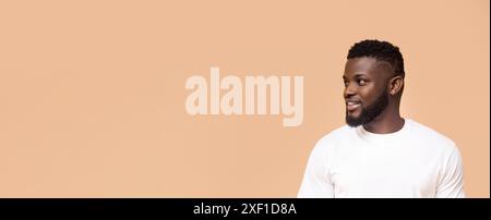 Smiling Black Man Looking Off Camera Against Light Brown Background Stock Photo