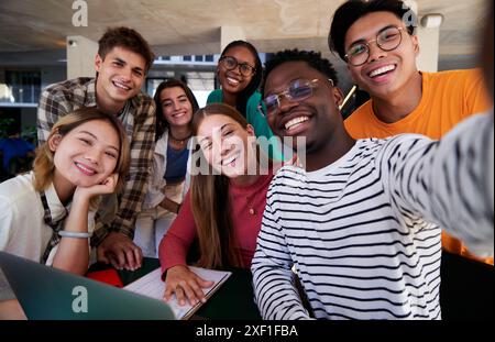 Happy selfie of a multiracial group of student friends gathered at university studying. Stock Photo