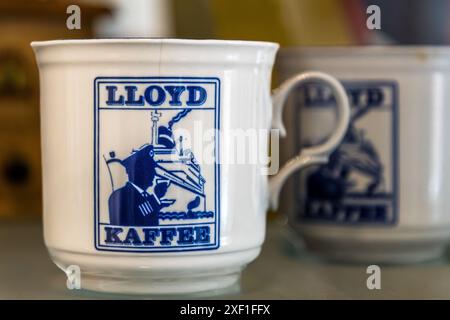 A mug with the Lloyd Caffee logo shows a coffee-drinking captain in front of an ocean liner, the emblem of the coffee roasting company founded in Bremen in 1930. Tasting room on Hagstraße, Bremen, Germany. Stock Photo