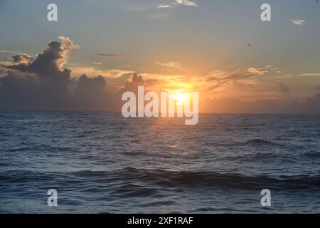 Sunrising through the clouds emitting God rays over the Atlantic Ocean Stock Photo