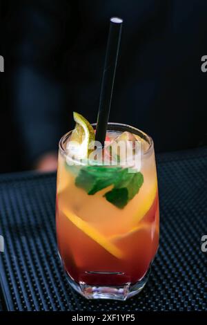 Cocktail with lime served in a Lagos bar - a glass of orange juice - mojito cocktail on a black background Stock Photo