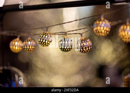 Hanging string lights with illuminated spherical bulbs against blurred background during traditional holiday Stock Photo