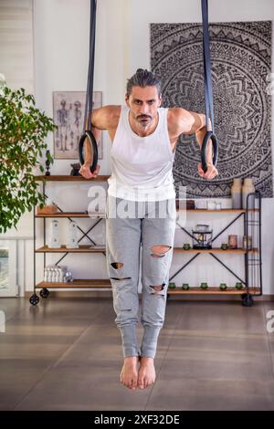 Fit man intensely performing ring dips, showcasing strength and focus in a  gym Stock Photo