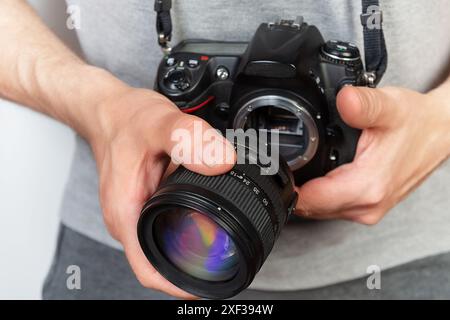 Close-up of a photographer holding a digital single-lens reflex (DSLR) camera and attaching the camera lens Stock Photo