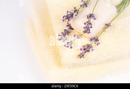 A stack of soft white towels with lavender flowers and a white bar of soap on top, creating a spa-like atmosphere. Stock Photo