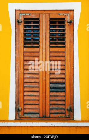 Old window with wooden shutters on yellow wall, vertical image Stock Photo
