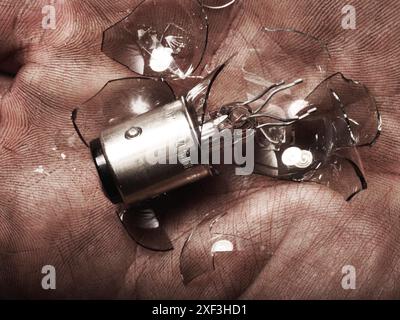 Dirty hand holding a broken light bulb Stock Photo