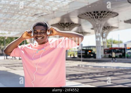 A man wearing a pink shirt is listening to music with headphones Stock Photo