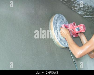Polishes and grinds surface with machine after mansonry.. Using manual polishing machine to polish cement wall Stock Photo