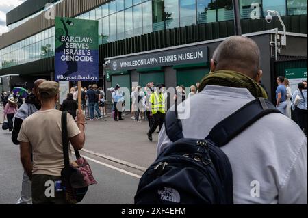 London, UK. 1st July 2024. Pro-Palestine demonstrator holding a sign that says “Barclays Serves Israel’s Genocide”. Pro-Palestine activists are asking for Wimbledon to “drop Barclays” over the company’s financial ties with Israel. Credit: David Tramontan / Alamy Live News Stock Photo