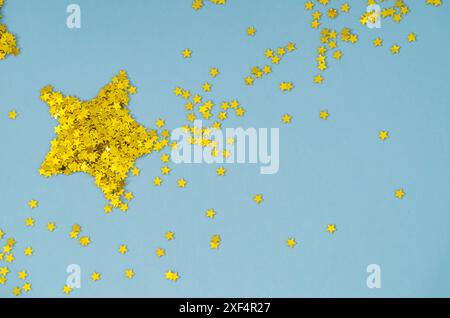 Golden glitter stars confetti on light blue background. Festive holiday pastel backdrop. Minimal concept. Flat lay. Stock Photo