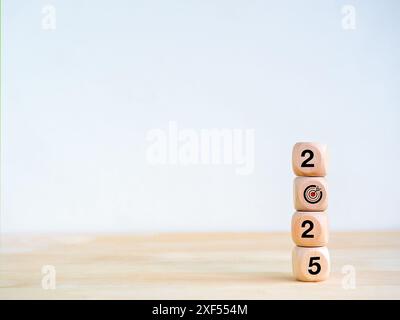 2025 Happy new year, minimal banner. Numbers and target dart icon on wooden cube blocks stacked, isolated on wood table, white background with copy sp Stock Photo