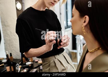 Hard working lgbtq makeup artist enhances womans natural beauty. Stock Photo