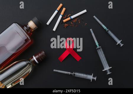 Flat lay composition with red awareness ribbon on black background Stock Photo