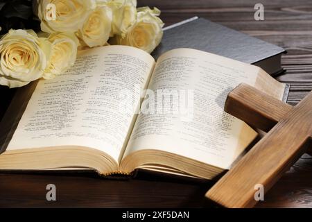 Bibles, cross and roses on wooden table, closeup. Religion of Christianity Stock Photo