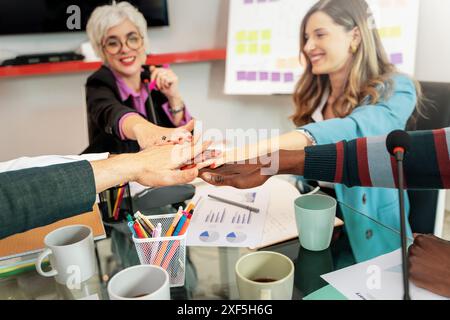 Diverse business team putting hands together in unity - professional collaboration, teamwork and engagement, corporate environment, working together, Stock Photo