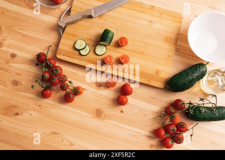 Slicing cherry tomatoes and cucumbers on a wooden table Stock Photo