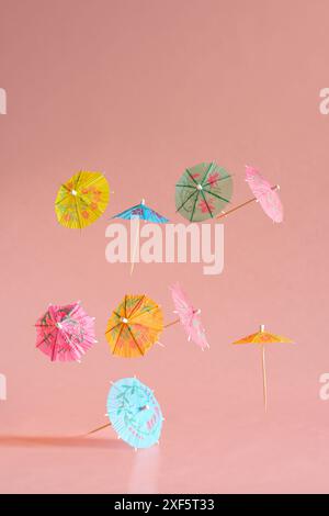 Floating Multicolored Cocktail Umbrellas, spring and summer symbol, rose background, free copy space Stock Photo