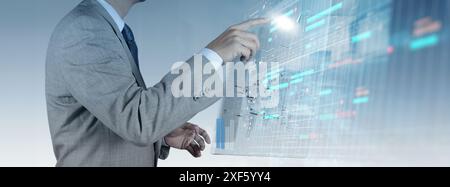 A businessman in a gray suit interacts with a futuristic digital interface displaying complex data, charts, and schedules. This image highlights the u Stock Photo