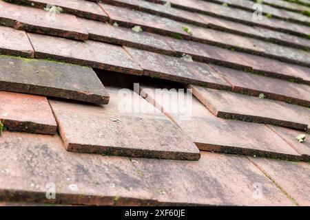 Missing and slipped plain clay roof tiles on a pitched roof of an old house in England, UK Stock Photo