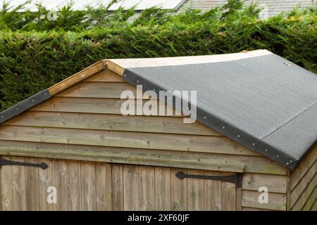 Replacing felt on a shed roof. Part of a series showing a roof being replaced on a shed in a UK garden. Stock Photo