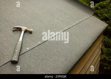 Replacing felt on a shed roof. Part of a series showing a roof being replaced on a shed in a UK garden. Stock Photo