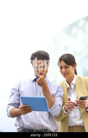 Business man and business woman with tablet and smartphone in business center. San Sebastian Technology Park. Donostia. Gipuzkoa. Basque Country. Spai Stock Photo