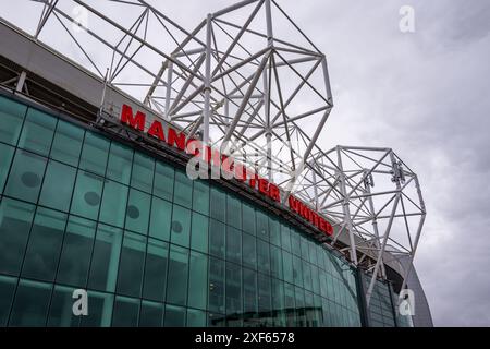 Manchester Trafford UK 29 June 2024. Exterior view of a modern stadium with striking architecture and bold signage under a cloudy sky. Stock Photo