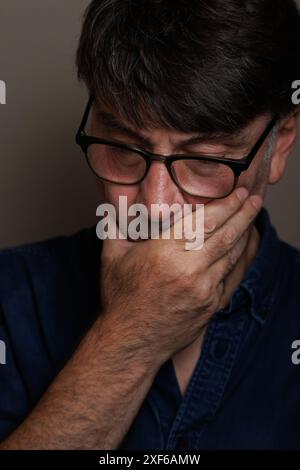 Middle aged man with hand on mouth because of toothache Stock Photo
