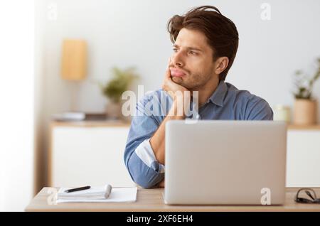 Man Thinking at Desk With Laptop Stock Photo
