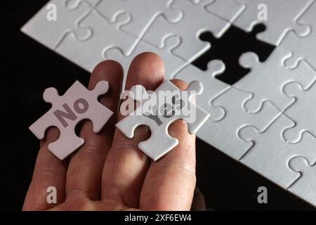 A hand holding two puzzle pieces with the word "no" on one and "yes" on the other Stock Photo