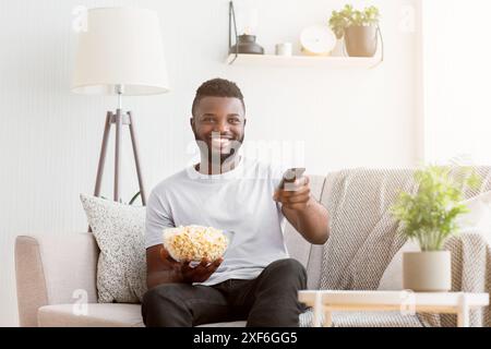 Man Relaxing on Couch With Remote and Popcorn Stock Photo