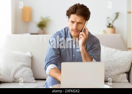 Man on Phone Call Working on Laptop at Home Stock Photo