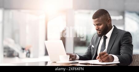 Businessman Working On Laptop Taking Notes In Outdoor Cafe Stock Photo