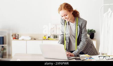 Smiling Woman Working On Laptop In Design Studio Stock Photo