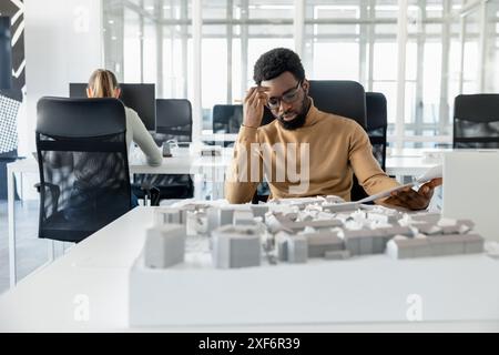 Dark-skinned young architect working in the office and looking tired Stock Photo