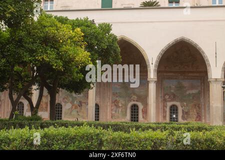 Beautiful cloister garden and frescs paintings on the walls of Santa Chiara Monastery, Naples, Italy. Vacation in Italy, Italian churches and park Stock Photo