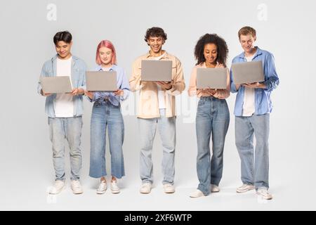 Diverse Group of Young Adults Using Laptops in Studio Setting Stock Photo