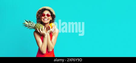 Smiling Woman Holding Pineapple and Orange on Blue Background Stock Photo