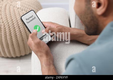 Man using online payment application on mobile phone at home, closeup Stock Photo